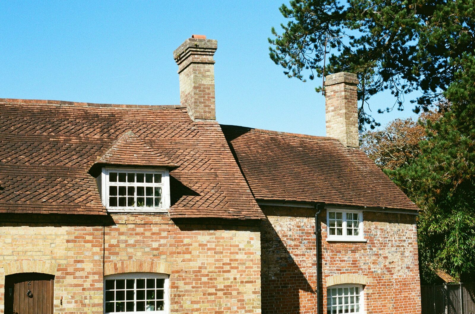 Traditional English brick cottage with clay tile roof and chimneys