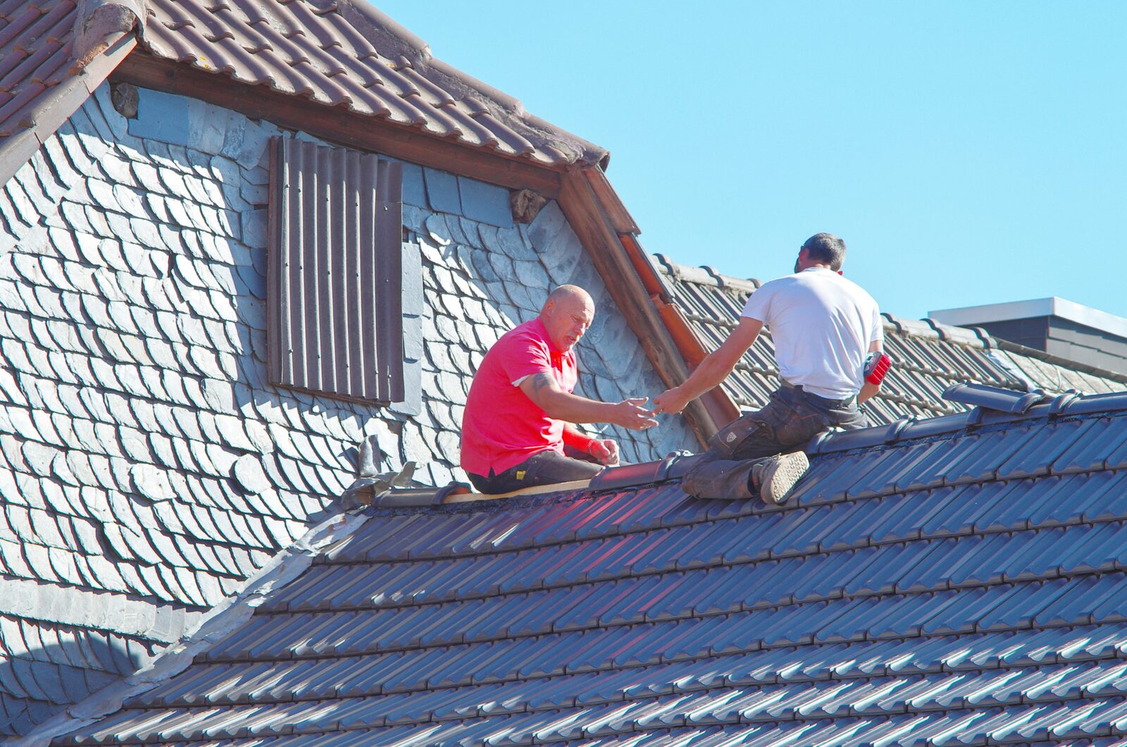 Roofers fitting new slates on a UK pitched roof